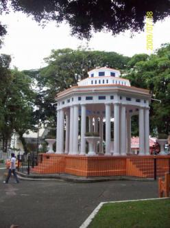 Turrialba, Costa Rica. The Central Park. ~  Cupola in the center of Turrialba's park is typical of Costa Rican towns.  

Downspouts from the roof water the plants in the urns. It is quite old, immaculately maintained and is fenced off. 