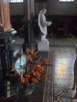 Inside the church in Zarcero, Alvaro Ruiz, Alajuela, Costa Rica ~  Statues, carved columns, tiled floors are common in Costa Rican churches. Flowers? Not so common. These are a common Heliconia known in English as "bird-of-paradise". 