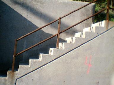 One of a number of staircases built into, not over, a concrete retaining wall.