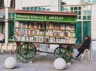 Selling books from a wooden cart designed like an old postal carriage.