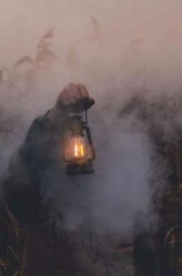 An arm lifts a lantern above the fog.