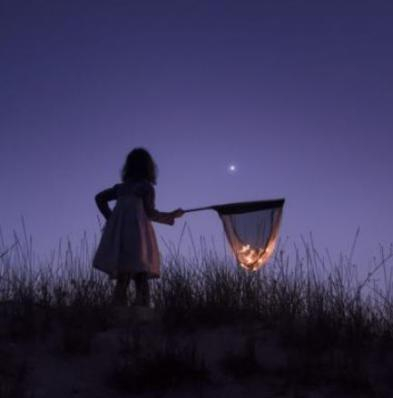 Little girl collecting fireflies at night.