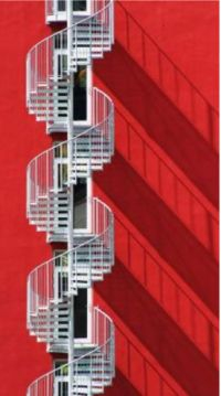 Spiral fire escape against red wall.