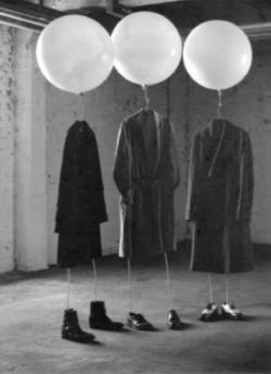 Empty suits and shoes suspended beneath balloons.