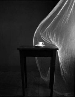 A curtain blows in the breeze to touch a table.