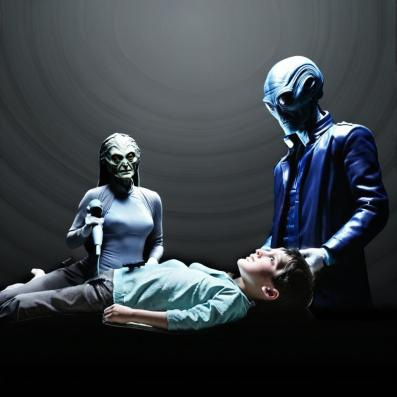 Terry is on an examination table with 2 alien grey's telepathically communicating.
